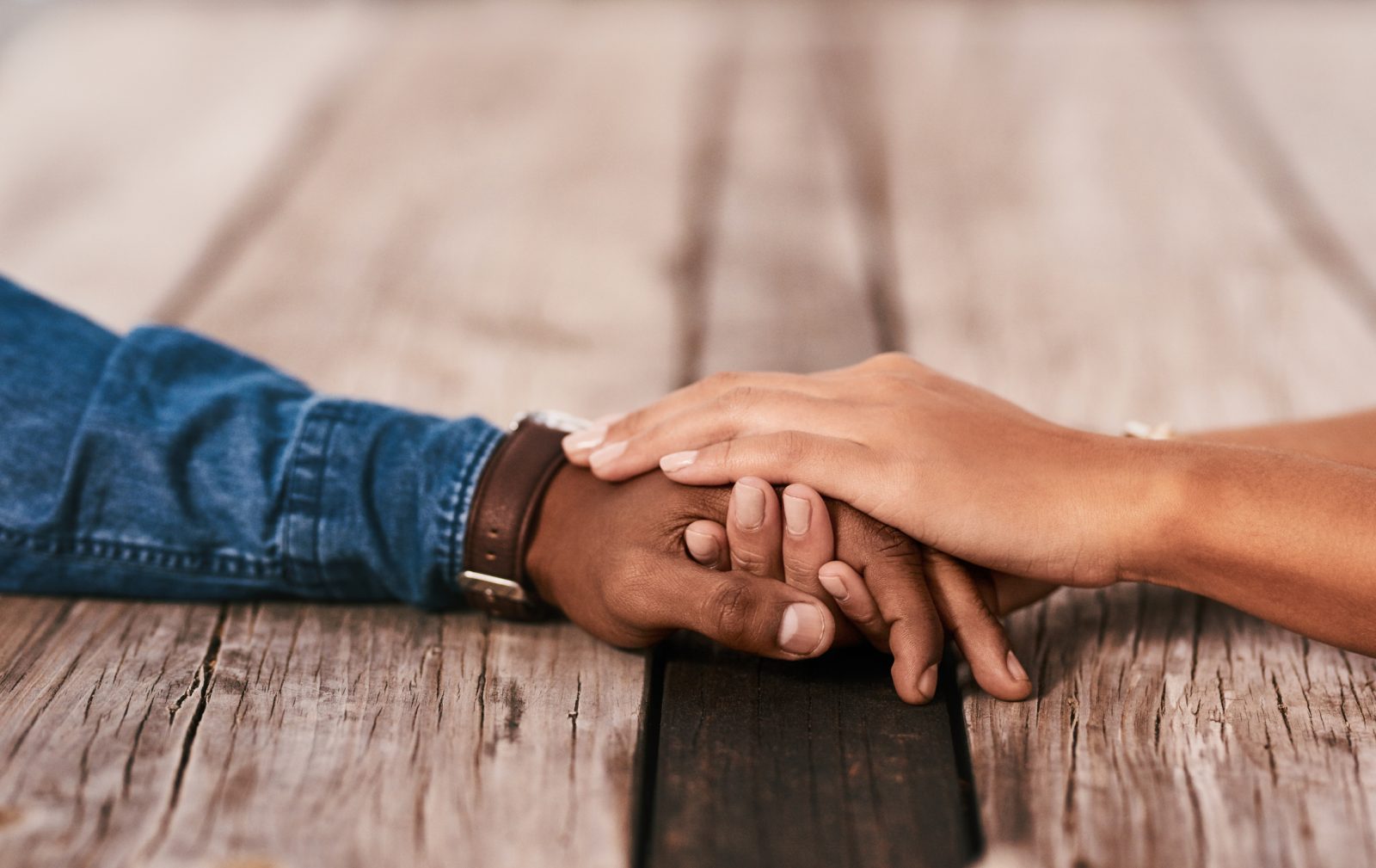 Close up of two people holding hands across a table