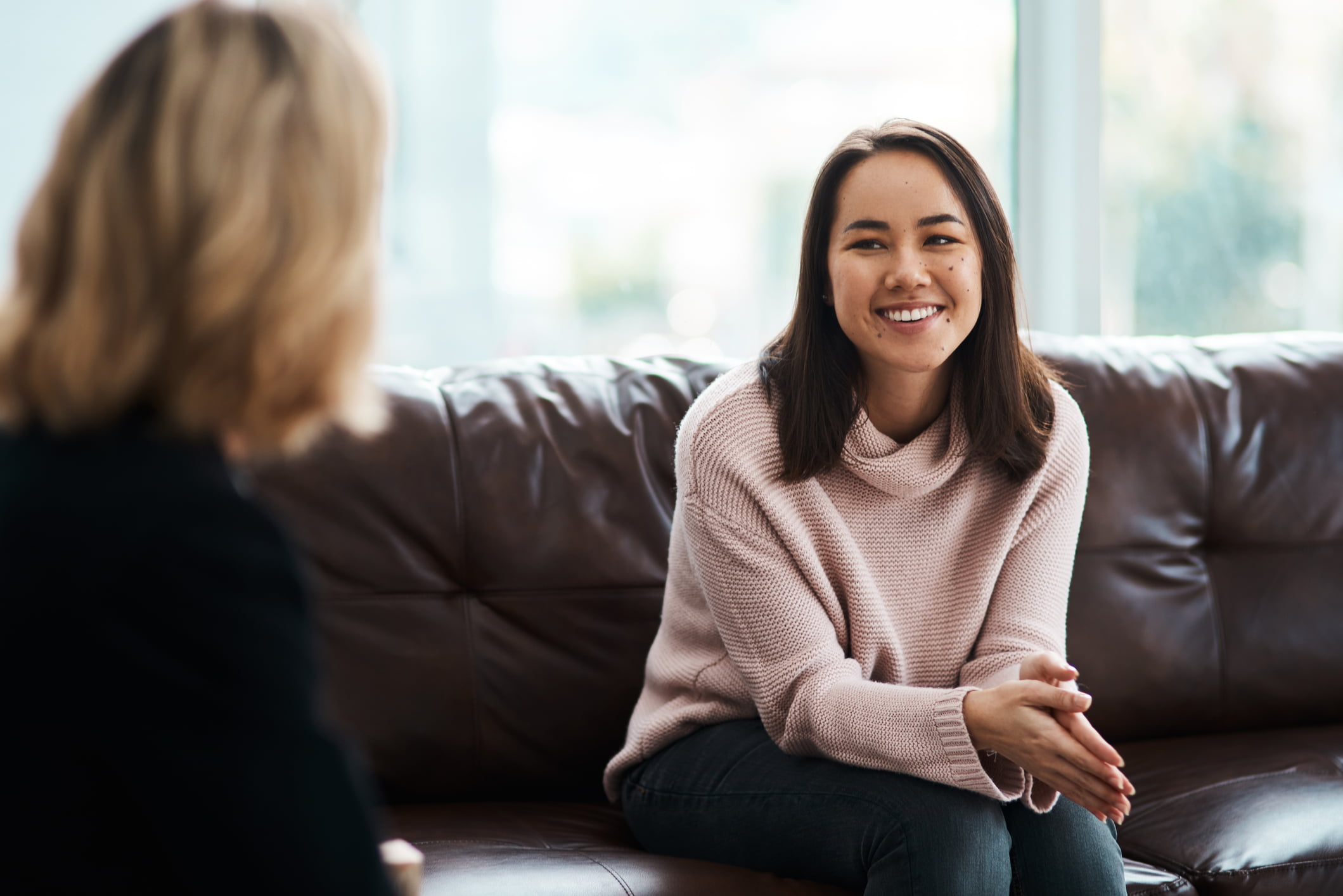 Young caregiver sitting on a couch facing another person