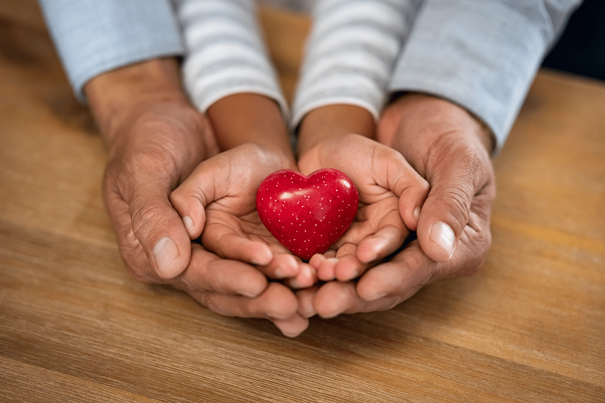 adult hands holding a child's hands, holding a heart